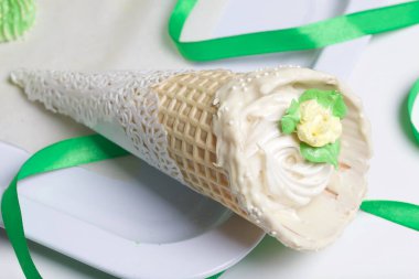 Şekerlemeli gözleme külahı. Beyaz çikolata ve çikolata parçacıklarıyla süslenmiş. Yakınlarda yeşil bir kurdele rüzgarı.