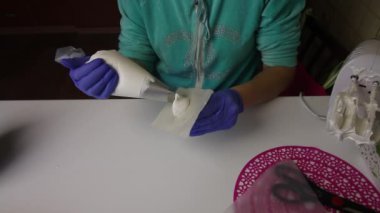 Hamur torbası ve hortum kullanan bir kadın marşmelovdan gül yaprakları oluşturuyor. Marşmelov Pişiriyorum.