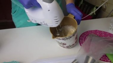 Konteynırda çırpıcı, reçel ve yumurta beyazı kullanan bir kadın. Bir lokum elde etmek için.