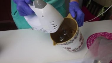 Konteynırda çırpıcı, reçel ve yumurta beyazı kullanan bir kadın. Bir lokum elde etmek için..