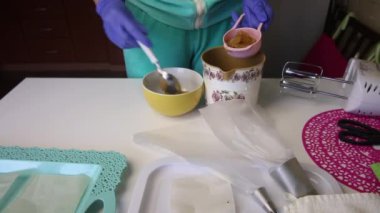 Bir kadın ölçüm kaşığına reçel koyar ve konteynıra koyar. Masanın yüzeyinin yanında marşmelov yapmak için araçlar vardır..