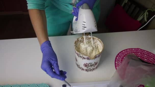 Een vrouw die een blender gebruikt bereidt een marshmallow in een container. Verwijdert het van de kloppers met een lepel. — Stockvideo