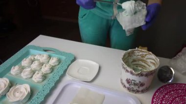 Bir kadın hamur torbasına şekerleme koyar ve boş kabı kenara koyar. Tepsinin üzerinde dengelemek için bir lokum var..