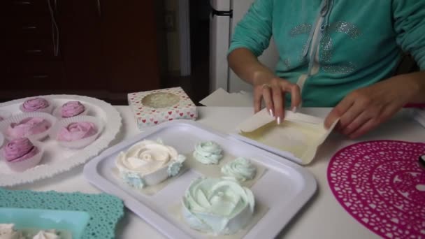 Marshmallows van verschillende vormen en kleuren zijn gelegd op trays voor stabilisatie. Een vrouw vouwt een geschenkdoos voor marshmallows. — Stockvideo