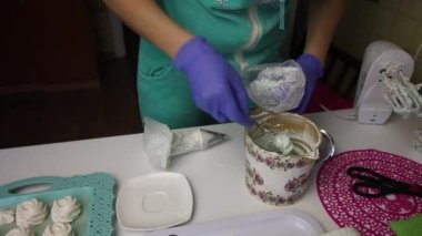 Bir kadın hamur torbasına marşmelov koyar. Tepsinin üzerinde dengelemek için bir lokum var.