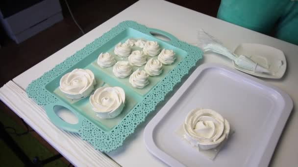 Na superfície da mesa em uma bandeja espalhar marshmallows em uma forma clássica e na forma de uma rosa. Um suporte com marshmallows na forma de uma flor de rosa é colocado no campo de visão . — Vídeo de Stock