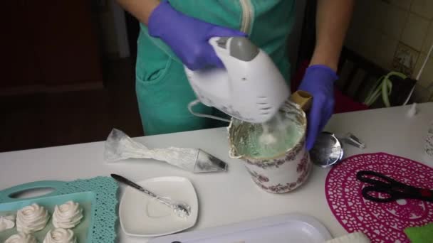 En kvinna blandar en marshmallow med en grön färg i en mixer. — Stockvideo