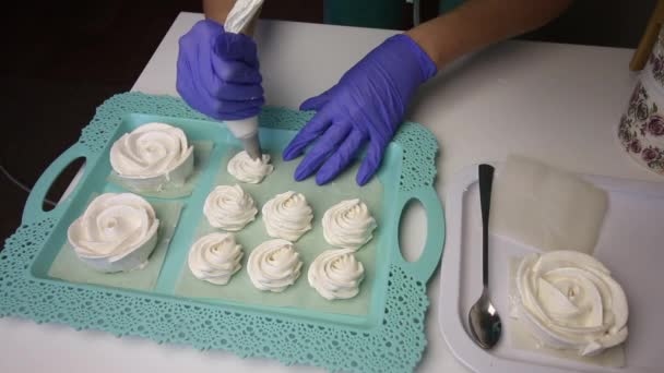 En una bandeja se encuentra un malvavisco en forma de rosa. Una mujer con la ayuda de una bolsa de pastelería forma un malvavisco de forma clásica junto a él. Situado en filas . — Vídeos de Stock