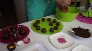 Kadın patates keki yapıyor. İş yüzeyine zum yap. Tabakların yanında kek kurusıkı, sıvı çikolata ve renkli serpinti var.
