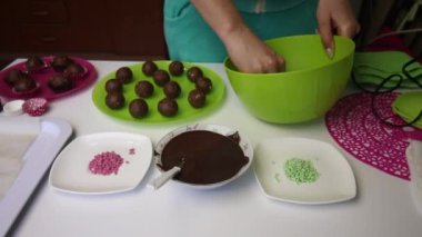 Kadın patates keki yapıyor. İş yüzeyine zum yap. Tabakların yanında kek kurusıkı, sıvı çikolata ve renkli serpinti var..