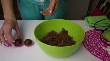 Bir kadın bisküvi hamurunu kağıda döker. Güç çıkışı. Sonra konteynırdan kütleyi alıp elleriyle yeni toplar yuvarlıyor. Kütle kahverengi, kurabiye ve kakao kırıntılarından yapılmış.