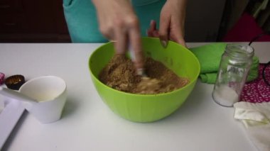 Bir kadın kurabiye kırıntılarını, kakaoyu ve tereyağını bir kabın içinde karıştırır. Patates kurabiyesi hazırlamak için bir ayin hazırlar..