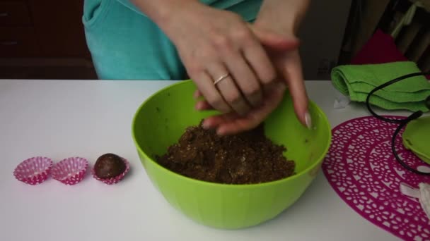 Een vrouw rolt ballen met haar handen uit een massa gemaakt van kruimels van koekjes en cacao, met de toevoeging van boter. Maakt losse flodders voor het maken van aardappelkoekjes. — Stockvideo