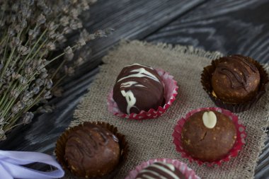 Çikolatalı patatesli kek. Cevizle süslenmiş, çikolata damlaları ya da serpiştirilmiş. Bir demet lavantanın yanında. Fırçalanmış tahtaların arka planına karşı.