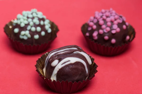 Cake Potato sponge cake covered with chocolate. Some are decorated with sprinkles, others with chocolate. Against the background of coral color.