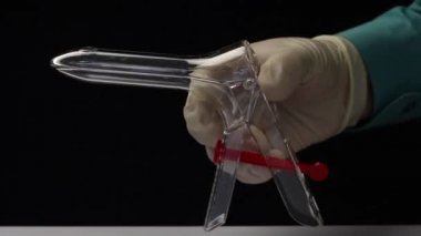 Lastik eldivenli bir doktor tek seferlik jinekolojik ayna gösteriyor. Jinekolojik spekulum Cusco. Yakın çekim..