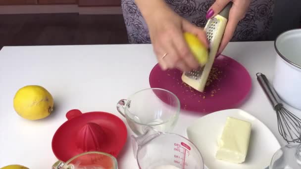 Girl with a grater prepares lemon zest. Then manually squeezes the juice from lemons. Cooking lemon Kurd. — Stockvideo