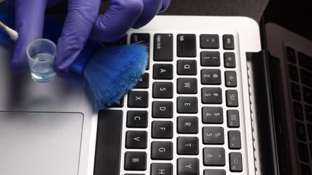Facet w gumowych rękawiczkach czyści laptopa. Zanurzyć wacik w środku czyszczącym i wyczyścić klawiaturę laptopa. Ochrona sprzętu roboczego przed zakażeniem wirusowym. — Wideo stockowe