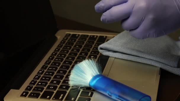 Een man zet een borstel om stof te verwijderen op een laptop toetsenbord. Hij neemt een wattenstaafje en dompelt het in een schoonmaakmiddel. Reinigt met een wattenstaafje tussen de toetsen. — Stockvideo