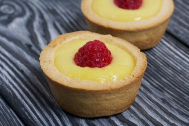 Limonlu turta. Ahududu ile süslenmiş. Çam ağacından siyah tahtalarda yatıyorlar..