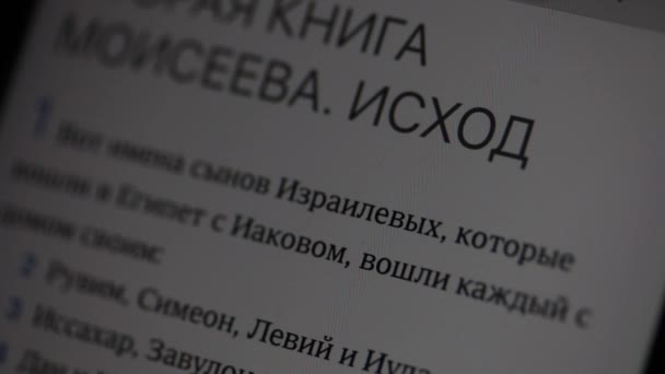 ロシア語の聖書の本出エジプト記はスマートフォンの画面で開いています。テキストがどのようにスクロールするかを確認できます。それはイースターのお祝いについての言葉にあります。. — ストック動画