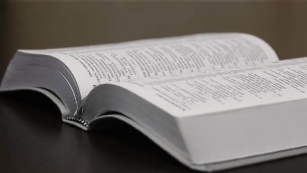 Na stole leży otwarta Biblia. Aparat zmienia ostrość z jednego obrotu na drugi. Strzał z bliska — Wideo stockowe