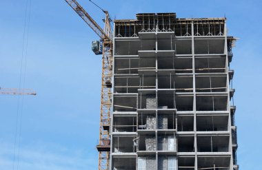 Yüksek binalar yapım aşamasında. Güçlendirilmiş beton çerçeve. Çift camlı pencerelerin kurulumu başlatılıyor. Görünür vinçler.