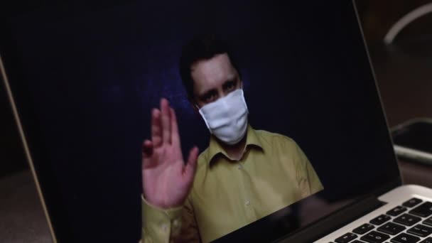 Een videoblogger met een medisch masker neemt een reclamevideo op op de webcam van een laptop op. Hij adverteert een keelspray voor abonnees. Voor de preventie en behandeling van virale infecties tijdens een — Stockvideo