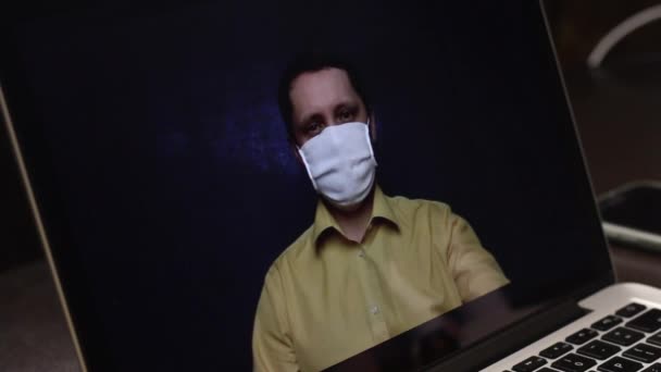 Een videoblogger met een medisch masker neemt een reclamevideo op op de webcam van een laptop op. Hij adverteert een neusspray voor abonnees. Voor de preventie en behandeling van virale infecties tijdens een e — Stockvideo