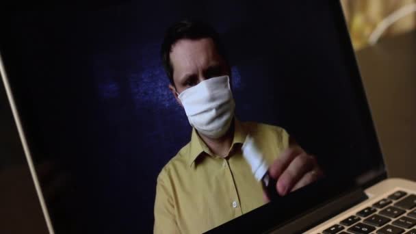 Відео блогер в медичній масці записує рекламне відео на веб-камеру ноутбука. Він представляє передплатникам засоби запобігання та лікування вірусної інфекції під час епідемії . — стокове відео