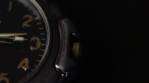 Auf dem Tisch liegt eine Armbanduhr. Ein Teil des Zifferblatts ist sichtbar. Die zweite Hand bewegt sich. Nahaufnahme, auf schwarzem Hintergrund. — Stockvideo