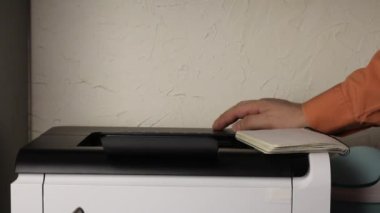 Bir adam lazer yazıcının yanında duruyor. Onaylanmış virüs enfeksiyonu vakalarının bir grafiğini ve bundan kaynaklanan toplam onaylanmış ölüm sayısını yazdırır. Yazıcı tepsisinden bir sayfa siler.