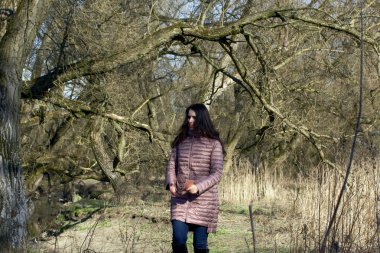 Bir kız bahar parkında yürüyor. Akıllı bir telefonun elindeydi. Fotoğraf çekmek için bir konu ararName.