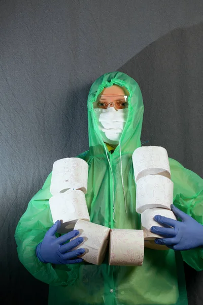 A man in a medical mask, glasses, rubber gloves and a raincoat. On the neck a bunch of rolls of toilet paper. Stocks for the time of the epidemic.