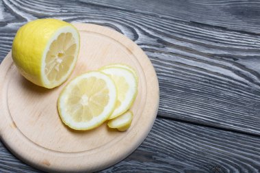 Kesme tahtasında dilimlenmiş limon. Fırçalanmış çam ağaçlarının yüzeyinde.