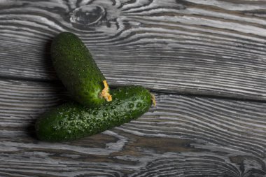 Sarı çiçekli iki yeşil dikenli salatalık. Fırçalanmış çam ağaçlarının yüzeyinde yatıyorlar..