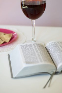 Bir bardak kuru kırmızı şarap ve mayasız ekmek tabakta yatıyor. Tanrı 'nın yemeğini kutlamak için. Yakınlarda İncil yatıyor..