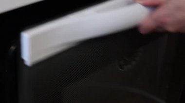 Kadın fırına yuvarlak bir hamur keki koyar. Elinde silikon bir minderle bir yemek tepsisinin üzerinde yatıyor. Taze bir tortilla hazırlar..
