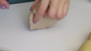 Bir kadın taze kekler için hamur topunu dikkatle yoğurur. Elleri masanın yüzeyinde diz çökmüş. Mayasız ekmek hazırlıyor. Yakın plan.
