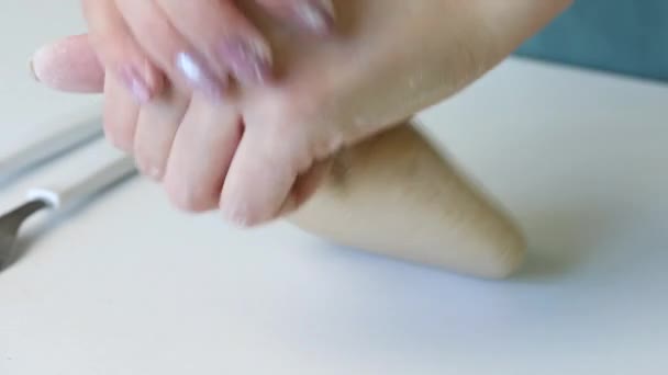 Een vrouw kneed een brok deeg voor verse taarten met haar handen. Vlakbij aan de tafel liggen deegroller en bloem. Bereid ongezuurd brood. Close-up — Stockvideo