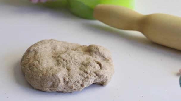 Op de tafel ligt een brok deeg voor verse taarten. Vlakbij aan de tafel liggen deegroller en bloem. Bereid ongezuurd brood. Close-up. — Stockvideo