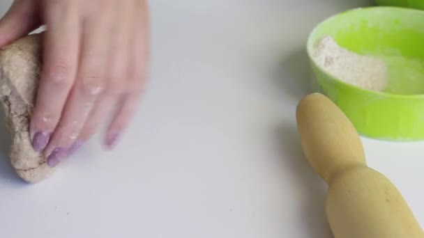 Een vrouw kneed zorgvuldig een bolletje deeg voor verse taarten. Knielen met zijn handen op het oppervlak van de tafel. Bereid ongezuurd brood. Close-up. — Stockvideo