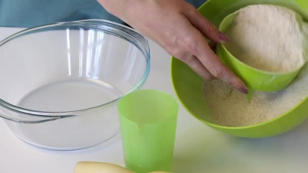 女性は発酵させないケーキの生地を作る。ガラス容器に小麦粉を注ぎ、少し水を追加します.未発酵のパンを用意する. — ストック動画