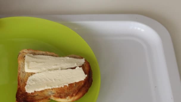 A man puts on a tray a plate with toast on which butter is laid. Nearby put a glass for coffee. Close-up shot. — Stock Video