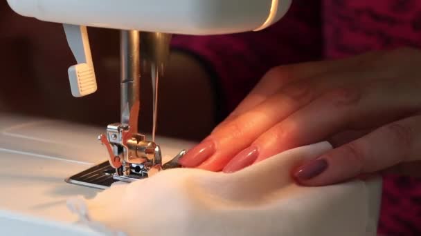 Kobieta szyje na maszynie do pisania maskę ochronną z tkaniny. Zbliżenie ujęcia z pracy uchwytu igły. Przyciąć nitkę nożyczkami. Praca w domu. — Wideo stockowe