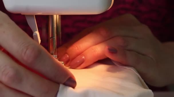 女性はタイプライターに布で作られた保護マスクを縫いつける。針ホルダーの仕事のクローズアップショット。自宅で働く. — ストック動画