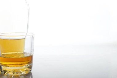 Sert alkollü cam şeffaf şişe. Bir bardak alkolün yanında. Beyaz bir arkaplanda.
