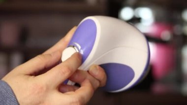 Adamın biri elinde elektrikli masaj aleti tutuyor. Çalıştırıyor, elinde inceliyor. Yakın çekim.