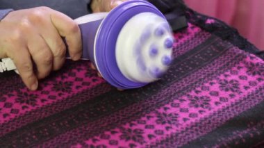 Adam elektrikli masaj aletini çalıştırıyor. Ayağına masaj yapmaya başlıyor. Yakın çekim..