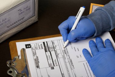 Kişisel izolasyon döneminde yazışmaların dağıtımı. Lastik eldivenli bir adam teslimat formu imzalıyor. Paket yakınlarda. Yakın çekim..